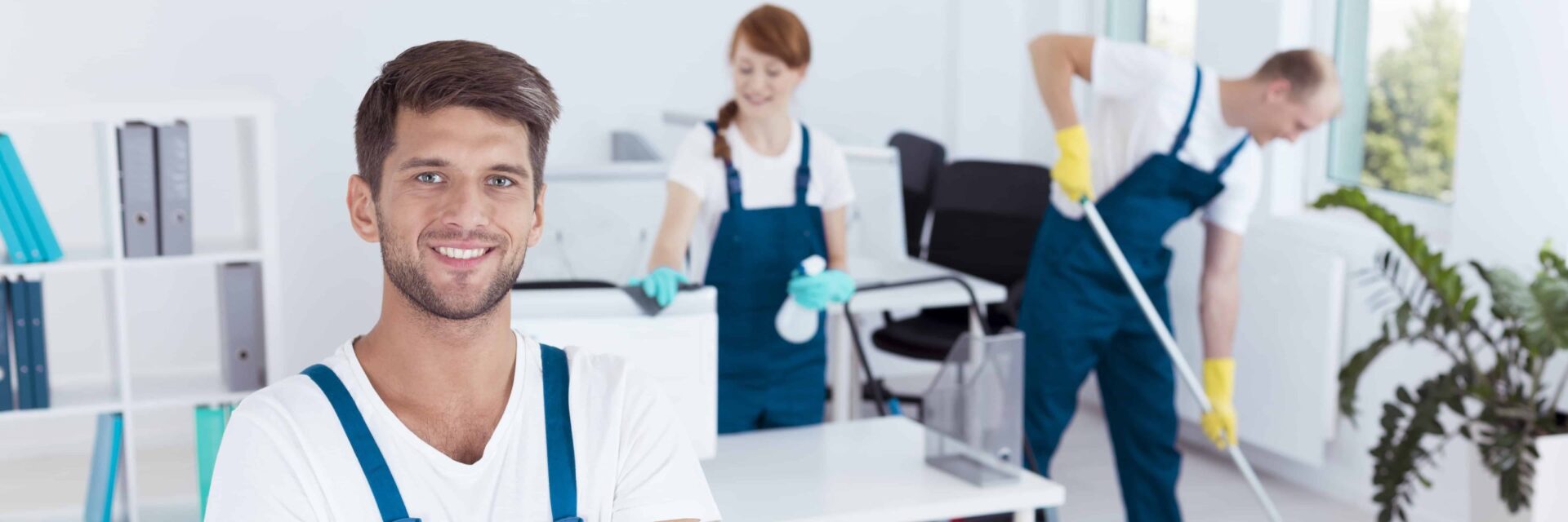 Man smiling while his team is cleaning in the background.