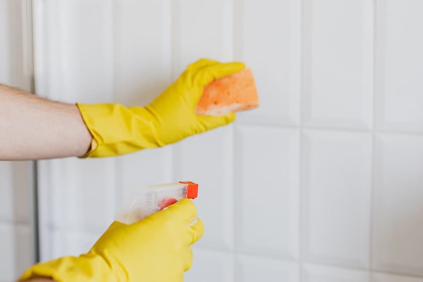 person in rubber gloves cleaning tiles